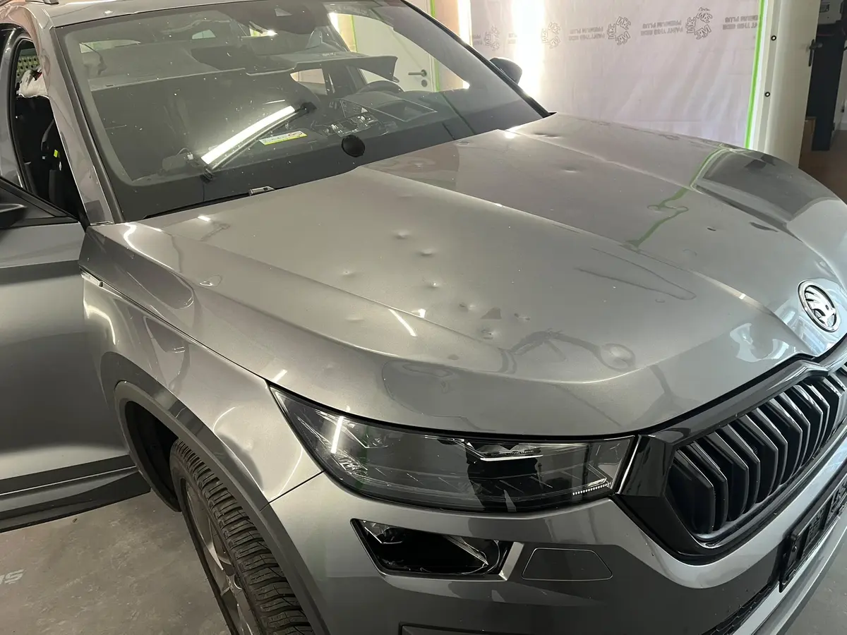 Viele Hageldellen auf der Motorhaube eines grauen SUV in unserer Werkstatt