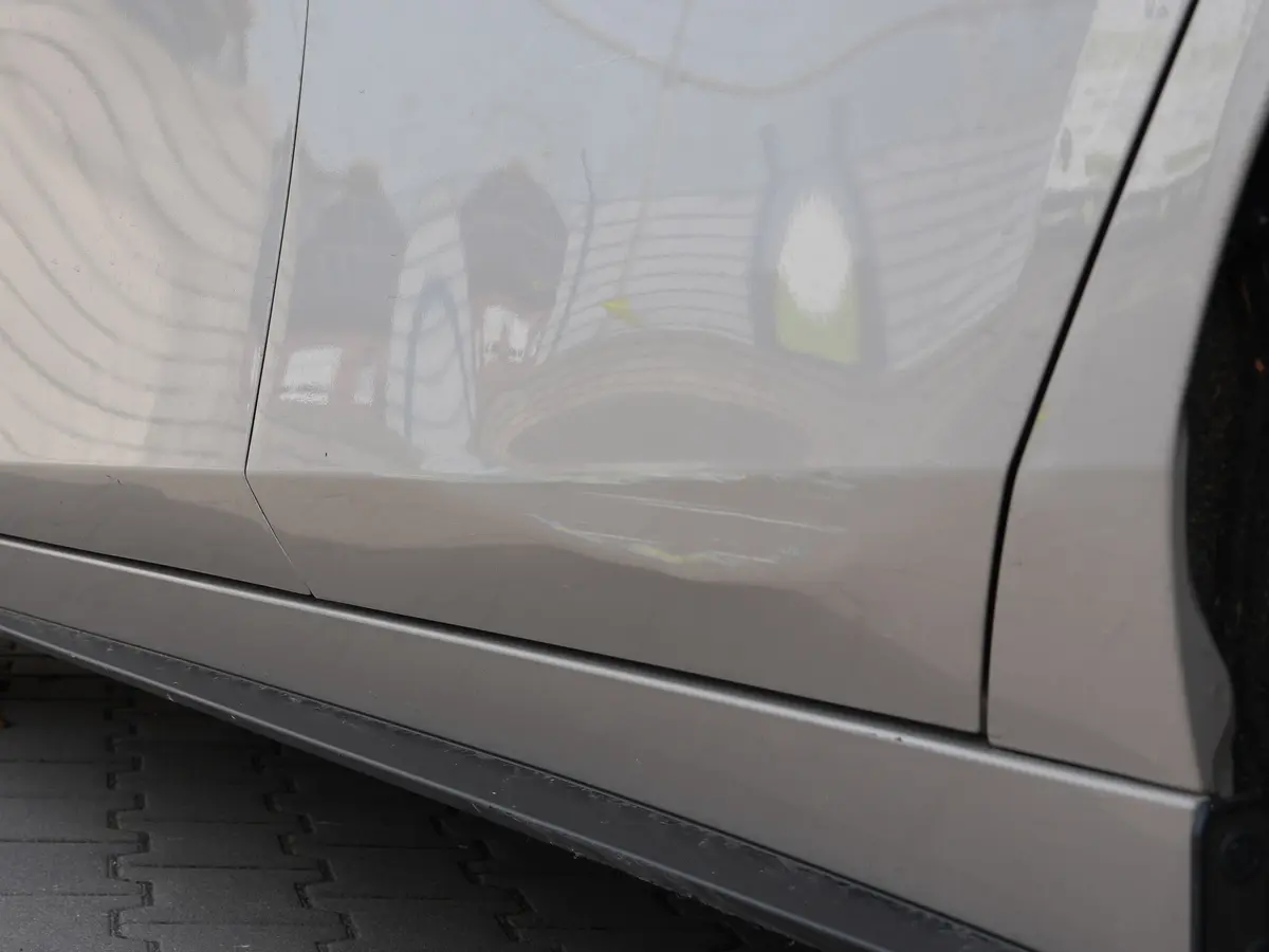 Delle in der hinteren Tür eines silbernen Autos, sichtbar an den verzogenen Spiegelungen