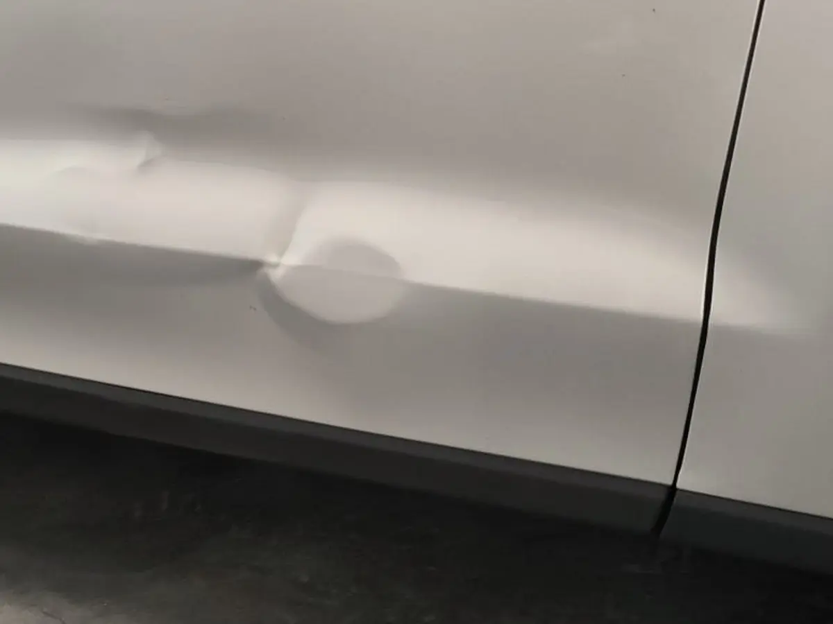 Vorher: große Delle unten in der hinteren Tür eines weißen Autos